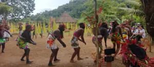 A group of individuals dressed in colorful attire perform a traditional dance in a rural setting.